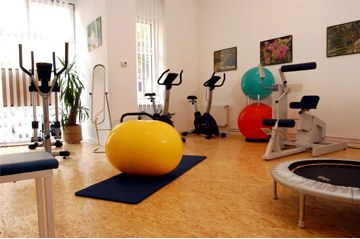 Trainingsraum der Praxis mit Gymnastikball, Ergometern,
                        Trampolin und Trainingsger&auml;ten.